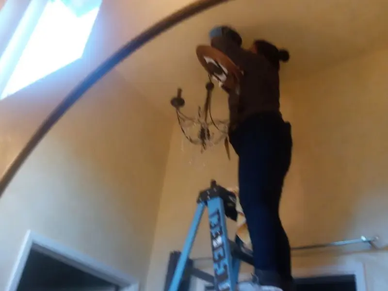 Electrician installing a chandelier in a Holt residence